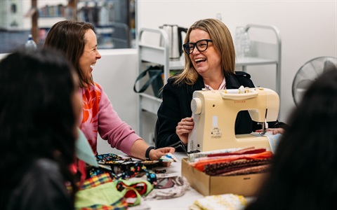 Two women laughing during a sewing workshop. 