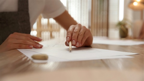 Young woman drawing with pencil at table indoors, closeup