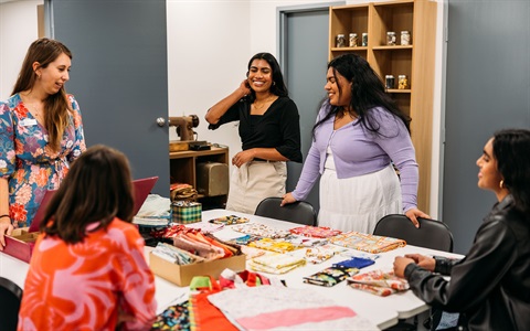 Young women chatting during a sewing workshop. 